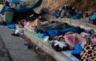 Migrantes del campo de Moria duermen junto a una carretera.