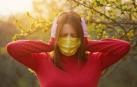 Una mujer con mascarilla se tapa los oídos.