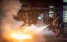 Un agente apaga las llamas de un cóctel molotov.