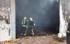 Dos bomberos, en la puerta de la nave que ha ardido.
