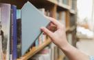 Imagen de una persona tomando un libro de una estantería