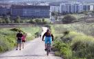 Un ciclista desciende por una pista, con Sarriguren de fondo.