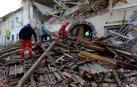 Personal de rescate camina entre los escombros de un edificio afectado por el terremoto en Petrinja (Croacia)