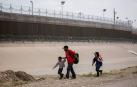 Un padre con dos niños intentan cruzar la frontera entre México y Estados Unidos atravesando el río Bravo