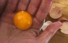 Imagen de una mano separando una yema de huevo de la clara