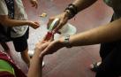 Una maestra dispensando gel hidroalcohólico a unos alumnos en el primer día del curso