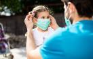 Un padre coloca una mascarilla a una niña