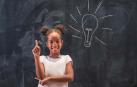 Una niña, frente a una pizarra en un aula