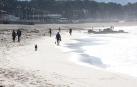 Varias personas caminan este martes en la playa de Samil de Vigo en una jornada soleada