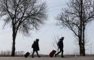 Refugiados caminan por una carretera saliendo de Mariupol