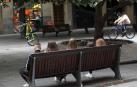 Unos jóvenes, en un banco y otros andando en bicicleta en el centro de Pamplona.