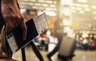 Una persona sostiene su pasaporte y el billete de avión