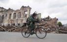Un ucraniano monta en bicicleta frente a un edificio destruido en Kharkiv, Ucrania