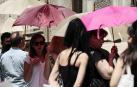 Varias personas se protegen del sol con paraguas en una calle de Valencia