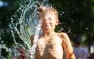 Un niño se refresca con agua en plena ola de calor