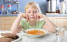Una niña, frente a un plato de comida