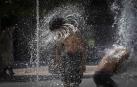 Dos jóvenes, refrescándose recientemente en la fuente de chorros de la Plaza de Yamaguchi en Pamplona
