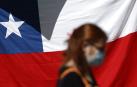 Una mujer camina frente a una bandera de Chile