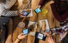 Un grupo de amigas consulta su móvil paga pagar la cuenta en un bar de Pamplona