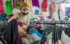 Una joven busca una prenda en una tienda de ropa de segunda mano