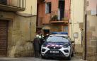 Un Mosso d'Escuadra habla con una vecina en la plaza Mayor de Artesa de Segre (Lleida) donde la policía catalana ha detenido a un hombre que ha provocado un incendio en un con su mujer en el interior