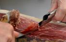 Imagen de archivo de una persona cortando un jamón