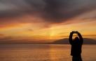 Una persona toma una foto del atardecer en una playa el último día del año