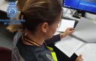 Una agente de la Policía Nacional analiza la documentación presentada sobre el timo del buen samaritano