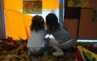 Dos infantes miran a través de la ventana de la Escuela Infantil Hello Egunsenti