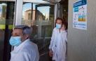Dos profesionales junto a la puerta de acceso del Hospital Universitario de Navarra donde había un cartel informativo sobre la huelga