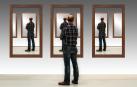 Un hombre observa su imagen repetida en varios espejos