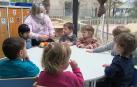 Una educadora prepara fruta a un grupo de niños en una escuela infantil de Pamplona