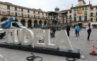 Varias personas contemplan el rótulo con la palabra 'Tudela' instalado en la céntrica plaza de los Fueros de la ciudad.