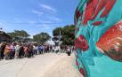 Asistentes a las visitas guiadas a las obras de la tercera edición del festival contemplan uno de los murales.