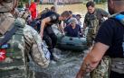 Policías y trabajadores de los servicios de emergencia estatales evacuan a personas de una zona inundada en el río Dnipro en la región de Kherson