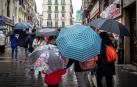 Varias personas caminan con paraguas por el centro de Pamplona