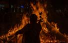 Un hombre tira papeles con sus deseos en la hoguera del barrio de Sant Antoni durante la noche de San Juan en Barcelona