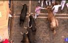 A tame bullock pushes a runner between two bulls in the running of the bulls in San Fermín