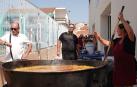 El concejal Joaquín Bermejo mira al reloj, mientras la cocinera se afana con la paella