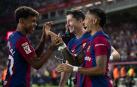 El delantero brasileño del FC Barcelona, Raphinha (d), celebra el cuarto gol del equipo blaugrana durante el encuentro correspondiente a la quinta jornada de primera división que disputan hoy sábado frente al Betis en el estadio Olímpico de Montjuic