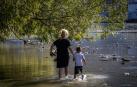 Una mujer y un niño se refrescan en las aguas del Arga, junto a las pasarelas de la Magdalena.