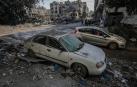 Un niño palestino mira un coche destruido por los bombardeos aéreos israelíes