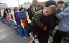 Una mujer porta en brazos a su hijo en un puesto de recogida de bombonas de gas al sur de la Franja de Gaza