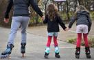 Dos niñas patinando con un adulto
