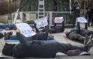 Representantes de Mugak Zabalduz se han echado en el suelo sobre esterillas mostrando carteles