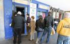 Un grupo de personas guarda cola en la Administración de Lotería de la plaza del Castillo de Pamplona para comprar lotería del sorteo de El Niño