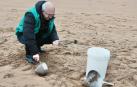 Un voluntario recoge pellets en la playa de La Arena, a 10 de enero de 2024, en Muskiz