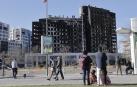 Varias personas observan esta mañana de sábado el edificio incendiado en el barrio de Campanar de Valencia
