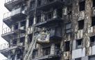 Bomberos, en una grúa, sanean la fachada quemada en el edificio calcinado en Valencia