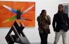 Dos personas pasan ante la obra de José Manuel Broto 'Relatos X' 2022 (acrílico sobre lienzo) en la feria de arte contemporáneo ARCO